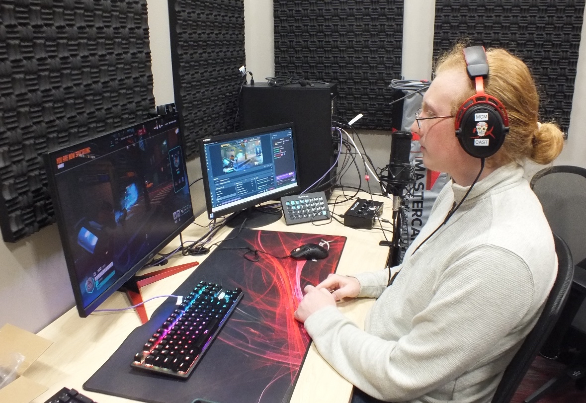 McMurry esports broadcaster using a microphone and multiple monitors